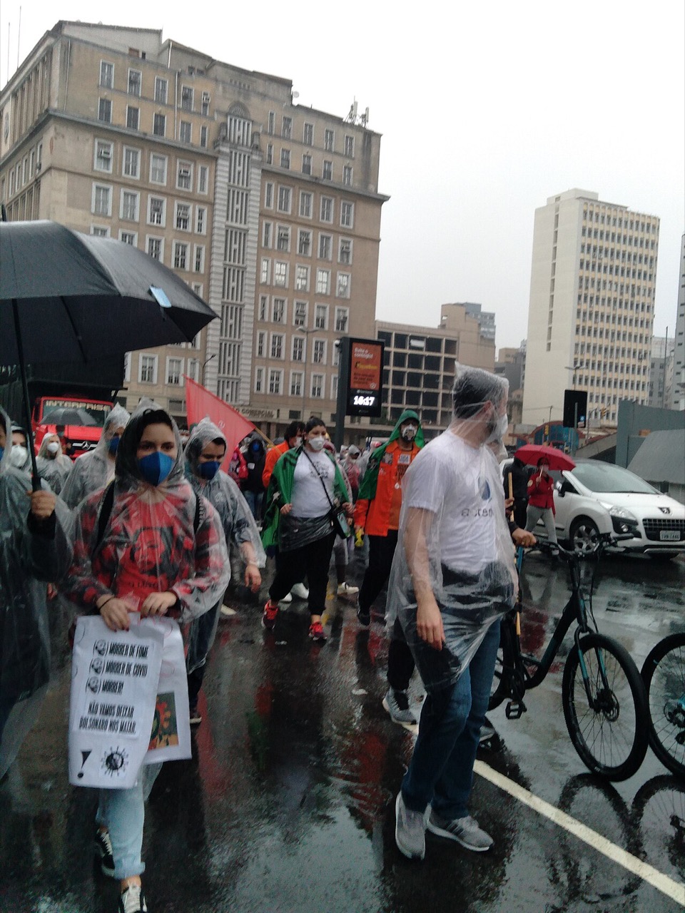 Passeata do 19J em Porto Alegre: manifestantes de máscara e capa de chuva marcham pelo centro, em 19/06/2021.